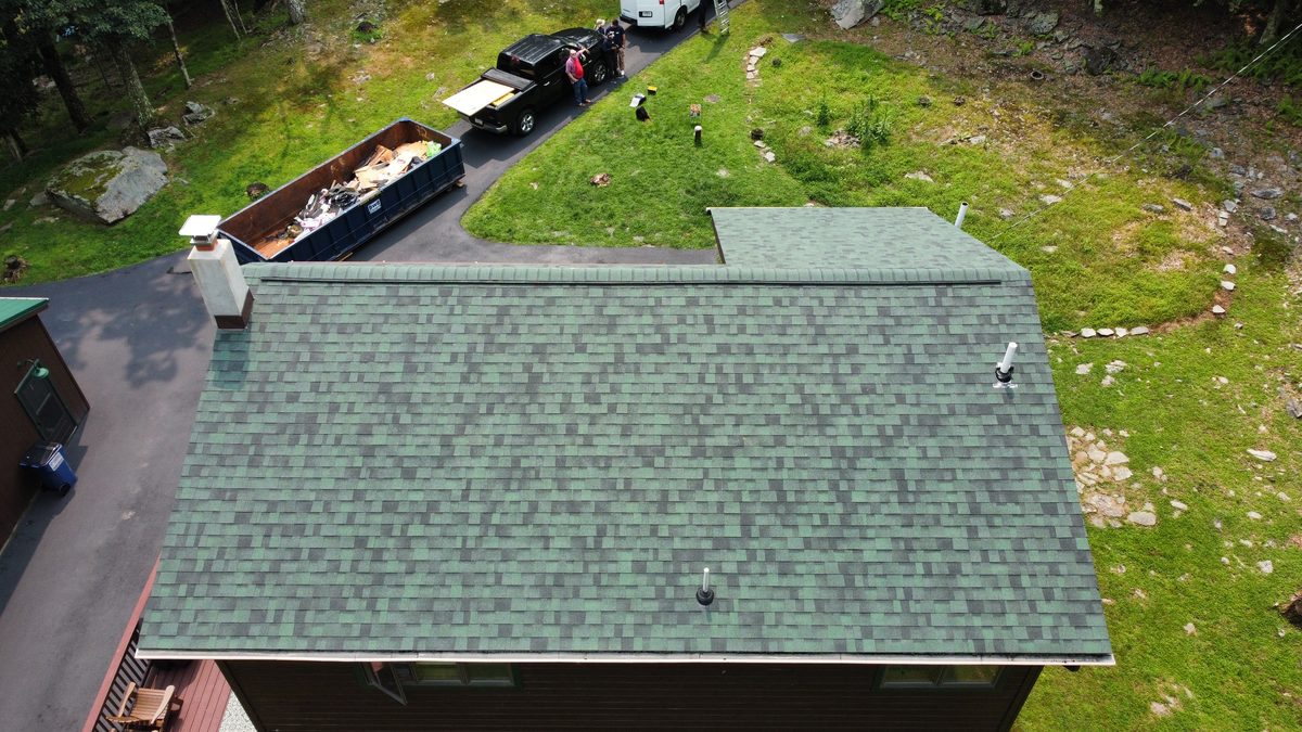 Roofing job site with dumpster staged and crew on the driveway
