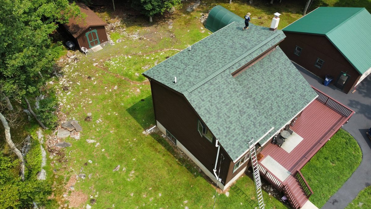 Roofer setting ridge cap on a newly shingled roof