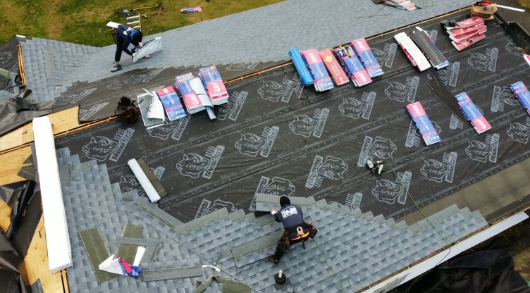 Roofing crew laying new shingles